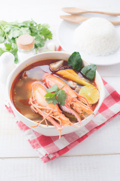 Tom Yam Kung (Thai cuisine) with rice on table wooden