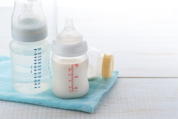 baby bottle and milk with pacifier on a white wood