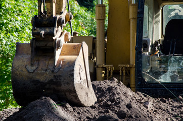 Fototapeta na wymiar Excavator with bucket resting on pile of dirt