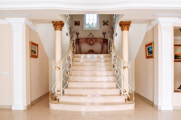 Luxurious staircase with marble steps and decorative and  ornamental iron railings. On the top are...