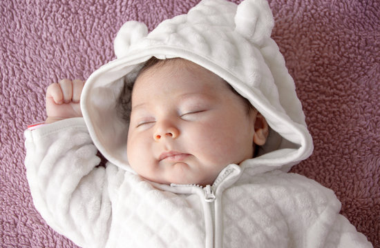 Newborn baby  on a purple background, picture from the top.  Newborn. Kid warmly dressed.