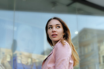 Beautiful girl turned on the background of the glass shop windows