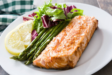 Grilled salmon fillet with asparagus and salad in plate on wooden table

