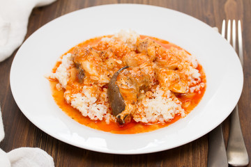 fish stew with rice on white plate on wooden background