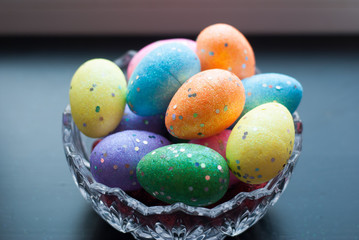 Easter eggs in crystal dishes on a black wooden background,