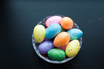 Easter eggs in crystal dishes on a black wooden background,