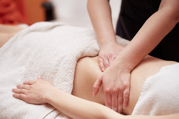Fototapeta na wymiar A woman receiving a belly massage at spa salon