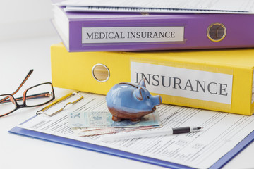 Clean insurance form, folders, pen, piggy bank and glasses