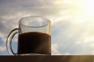 Cup of hot coffee on blue sky with clouds and sun  background