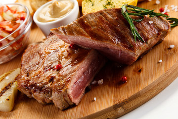 Steaks, baked potatoes and vegetable salad