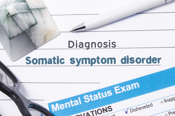 Psychiatric Diagnosis Somatic Symptom Disorder. Medical book or form with the name of diagnosis Somatic Symptom Disorder is on table of doctor surrounded by questionnaire to determine mental state