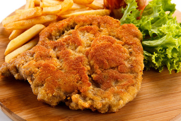 Fried pork chop with french fries on cutting board