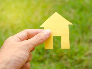 Hand holding House paper with field grass background.Concept of Home loan,Insurance