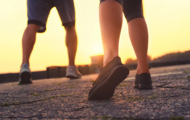 man's legs and a girl in sneakers running at sunset.