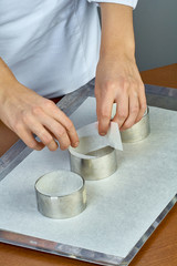 The cook pours the dough into forms for making cupcakes