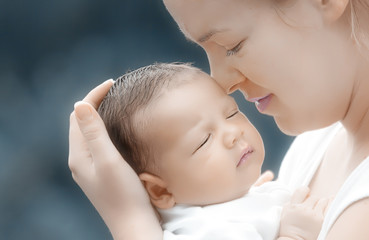 liebende Mutter hält träumendes Baby im Arm,nahaufnahme