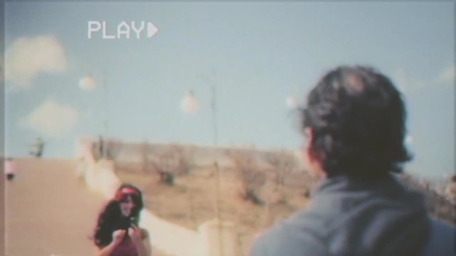 Fake VHS tape: an ugly man kneeling in front of her girlfriend at a romantic place and showing an engagement ring. The woman runs away with the excuse of taking a picture.
