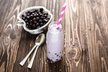 Homemade milkshake with berries on wooden background