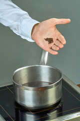 The cook sips the ingredients in a pan for cooking mulled wine full of culinary recipes