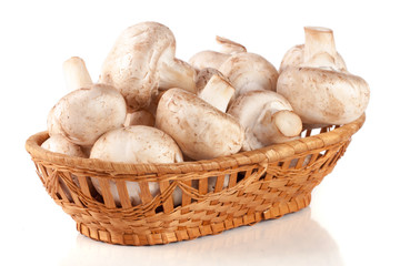 Champignon mushrooms in a wicker basket isolated on white background