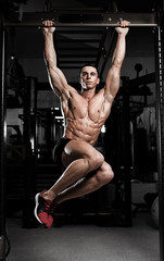 Fototapeta premium Athlete muscular fitness male model pulling up on horizontal bar