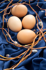 4 eggs in a willow nest on blue fabric
