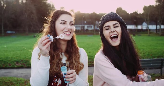 Beautiful happy girls blow bubbles. Slow motion.