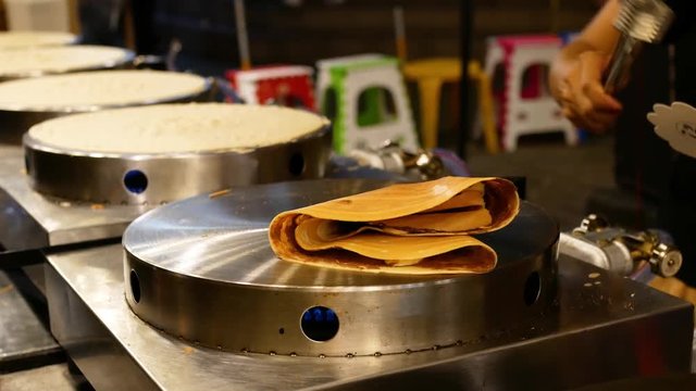 Street vendor cooking delicious pancakes for sale.