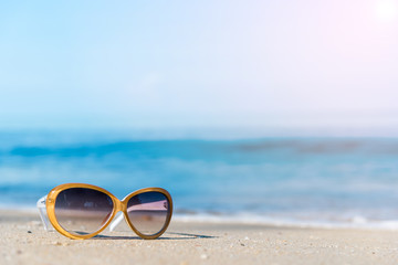 Fototapeta na wymiar Fashion sunglasses on the beach, blurry blue sea and sky background 