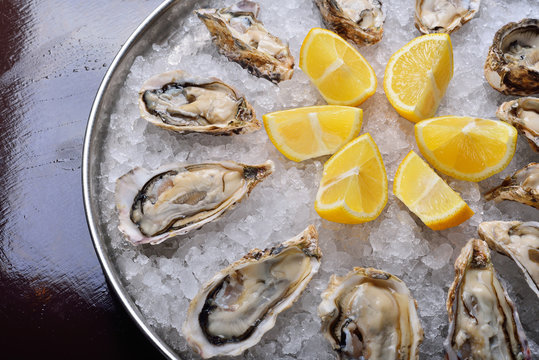 close-up on oysters on ice, lemon and water splashes. The concept of an expensive restaurant