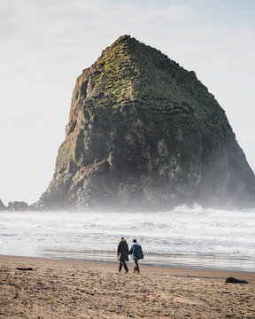 Couple walking on the coastal beach near Haystack Rock