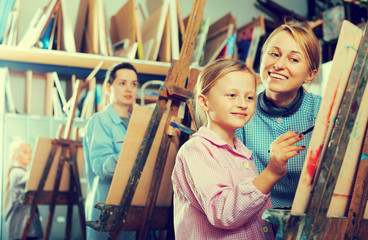 Obraz na płótnie Canvas Female teacher helping girl during painting class
