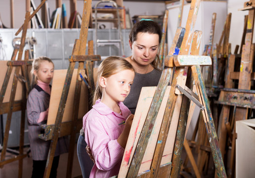 Female teacher helping girl during painting class