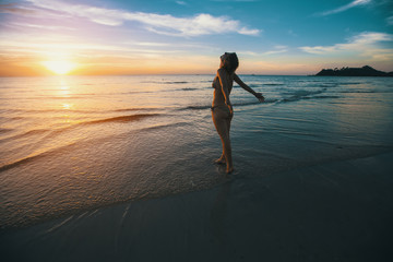 Fototapeta na wymiar Woman standing on the beach during beautiful sunset.