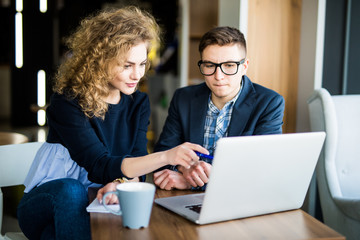 Group of two coworkers working over laptop discuss in a modern office. Woman pointed on screen