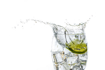 Close up of lime slice dropped in water glass.