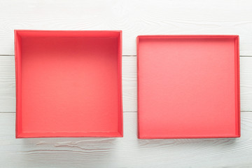 Opened empty red box with lid on white wooden background. Flat lay. Top view with copy space