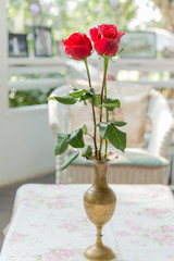 Red rose in brass vase on the table vintage style
