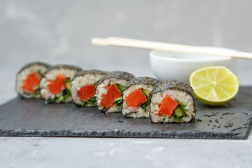 Healthy homemade sushi rolls with brown rice, fish and green vegetable rolls.
