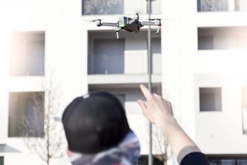 young guy is flying a drone with remote control outdoor