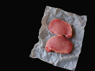 Raw pork chop steak on black background.