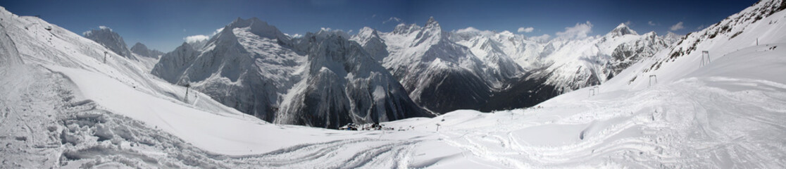 Obraz premium Winter panorama of a mountain landscape, snow-capped peaks and slopes.