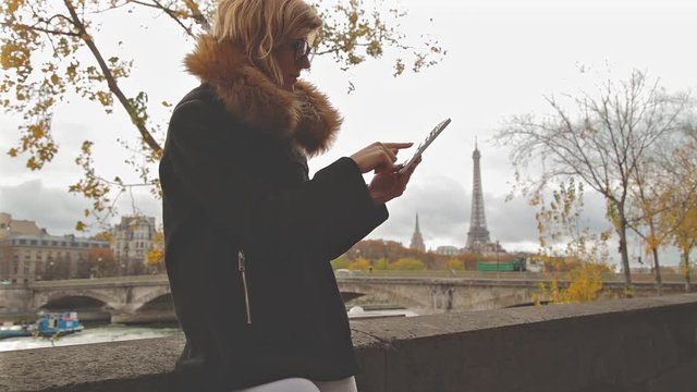 Cute girl using cellphone with Eiffel tower in the background, Paris - France.