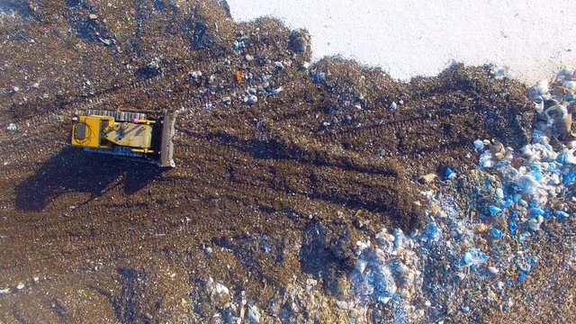 4K. Dozer, bulldozer working at the garbage dump. Directly from above. Aerial shot. 4K