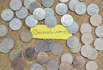 A lot of coins lying on the background of burlap with a label with the words for a donation. Ukrainian coins. Sacrifice. To help. Do not be indifferent
