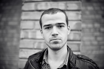 Intense black and white portrait of  man in leather jacket outdoors