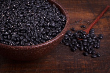 Black beans in scoop on wooden background