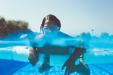 Underwater fun. Cute little girl with goggles swimming underwater and diving in the swimming poll. Sport and leisure. © Dusko