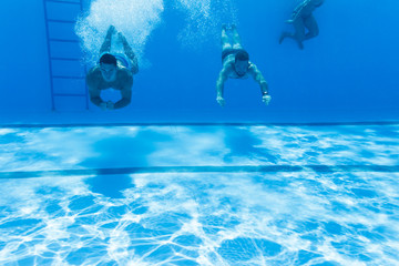 Underwater fun. Two young handsome men swimming underwater and diving in the swimming poll. Sport...