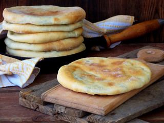 A pile of Georgian pies with cheese and spring greens on a wooden background
